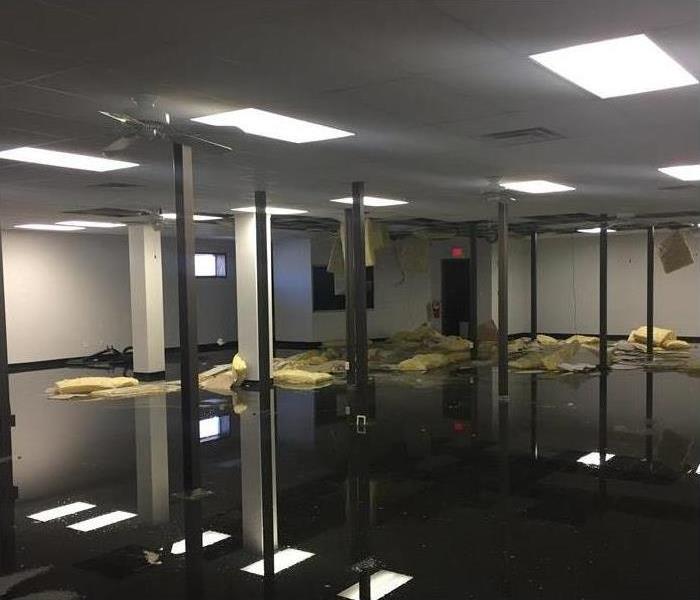 Empty commercial building, standing clear water on the floor, insulation from ceiling on the floor