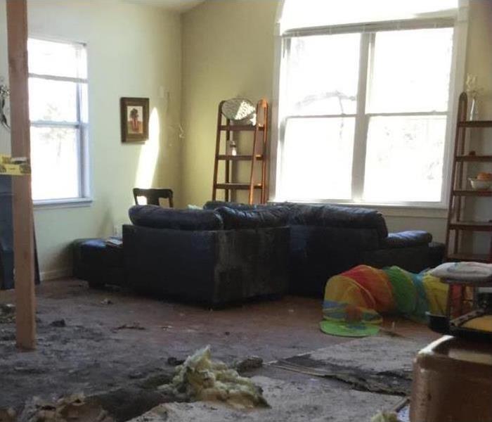 Interior of a home damaged by fire, couch, debris on the floor pieces of ceiling on the floor